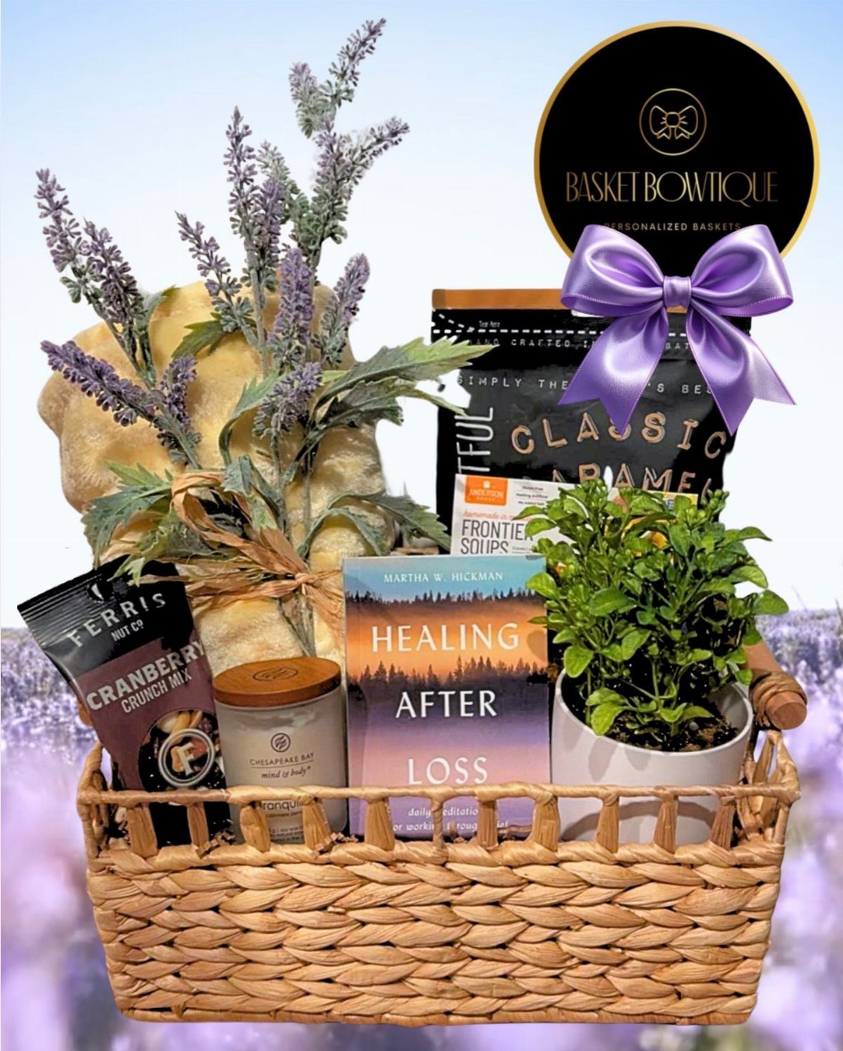 Woven gift basket with a healing book, potted plant, candle, and lavender sprigs.