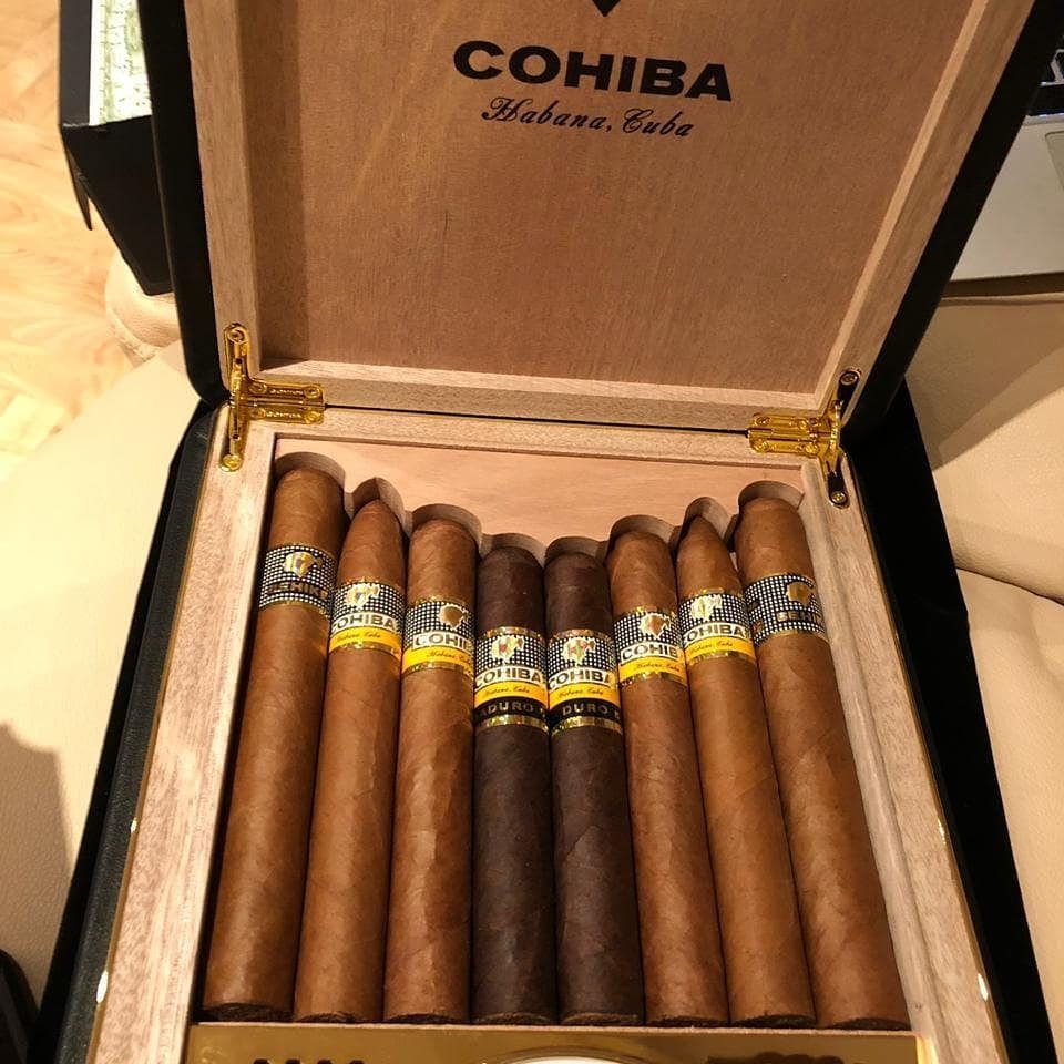 17 Anniversary Boyfriend Gifts He'll Actually Use (2026) 15 Open wooden cigar humidor filled with Cohiba cigars with yellow and black bands.