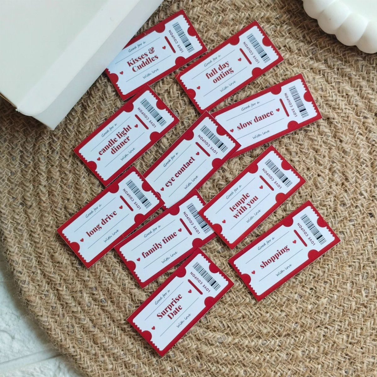 17 Anniversary Boyfriend Gifts He'll Actually Use (2026) 13 Red and white love coupons scattered on a woven straw mat.