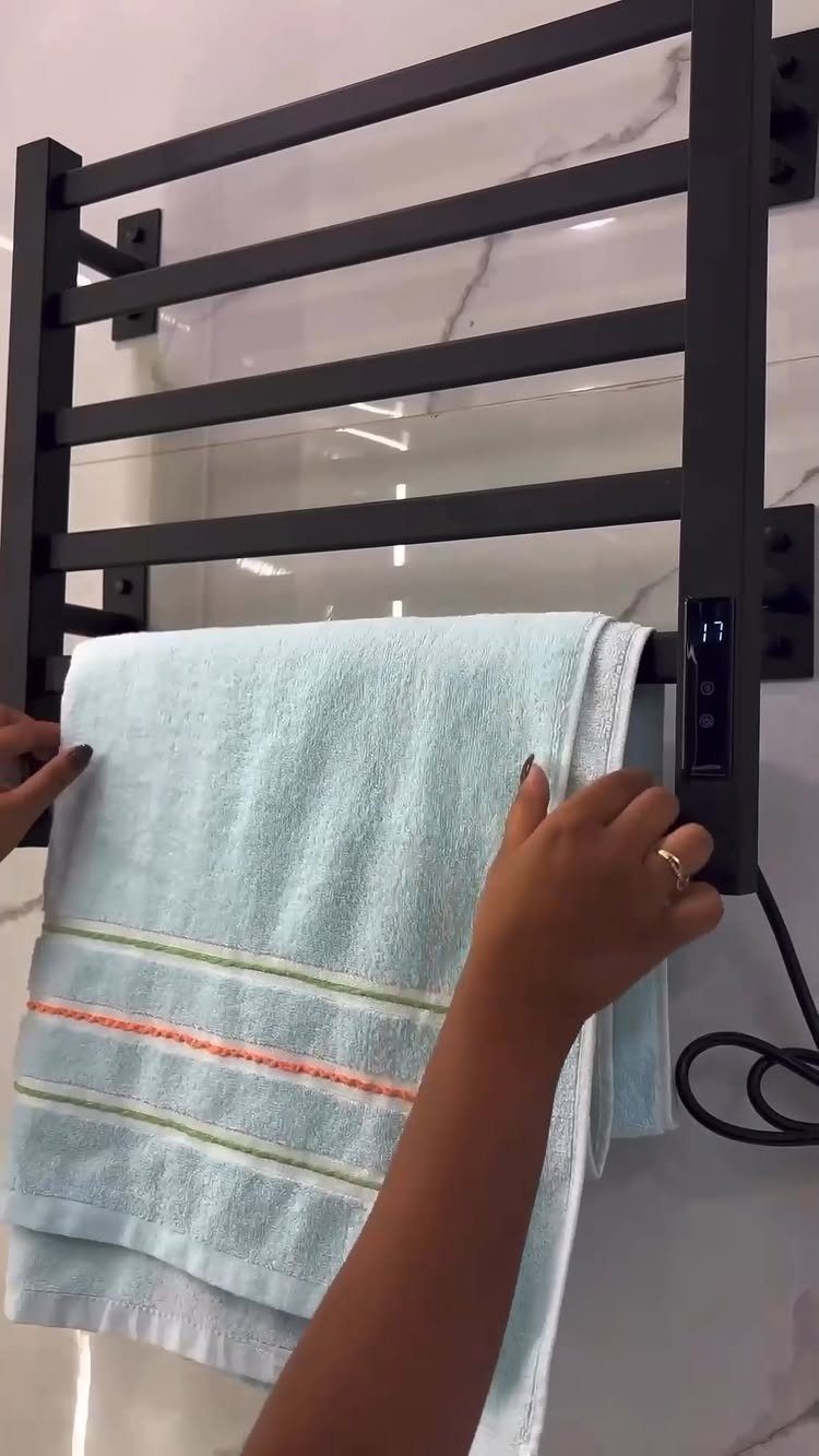 8 Bathroom Gift Ideas for Spa Nights and Everyday Use 5 Black heated towel rack on marble wall with a light blue towel hanging.