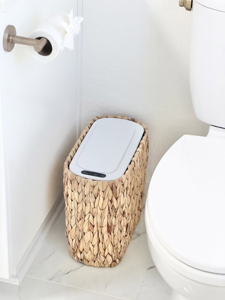 8 Bathroom Gift Ideas for Spa Nights and Everyday Use 7 Woven wicker mini trash can with white lid next to a white toilet.