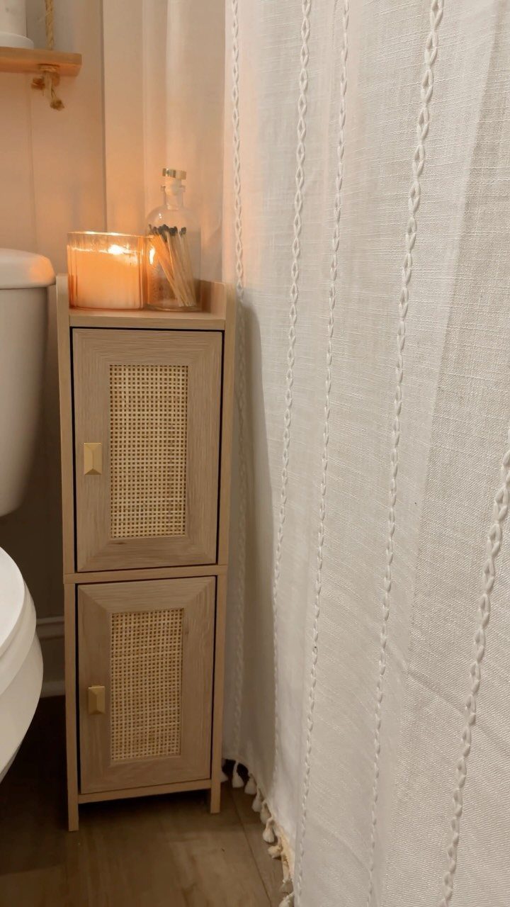 8 Bathroom Gift Ideas for Spa Nights and Everyday Use 1 Light wood bathroom cabinet with a lit candle and glass jar on top.