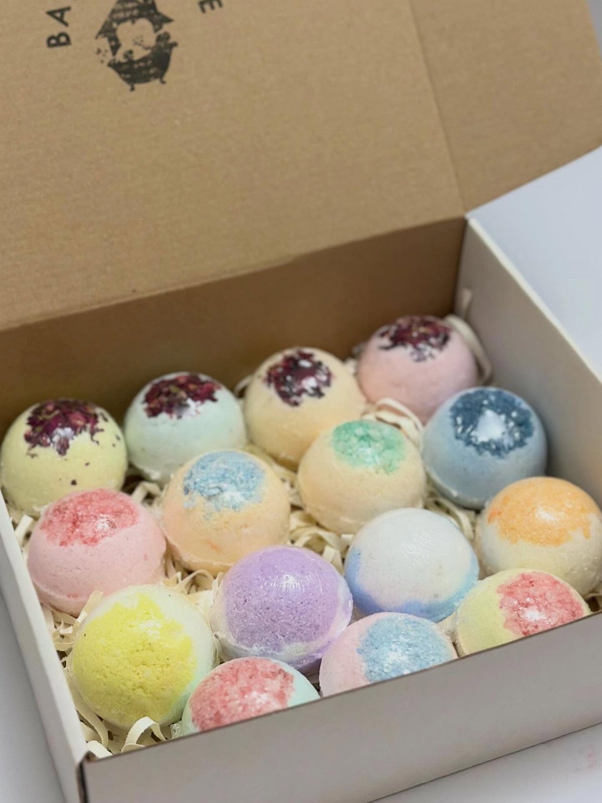 8 Bathroom Gift Ideas for Spa Nights and Everyday Use 4 Colorful spherical bath bombs in a white gift box with shredded paper filler.