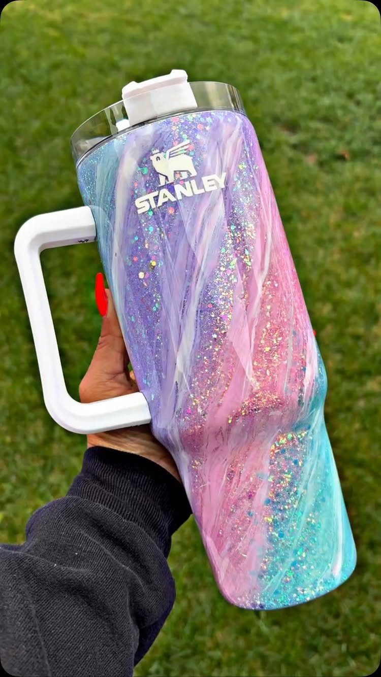 Glittery purple and pink Stanley tumbler held against a green grass background.