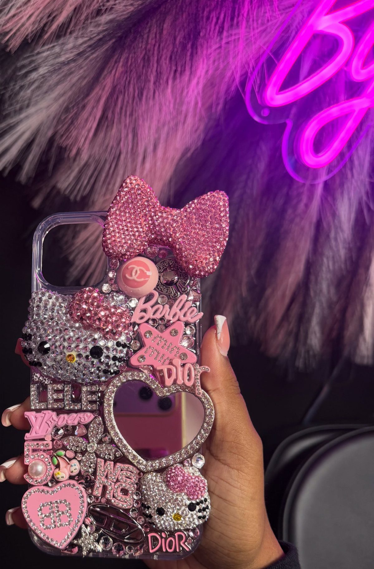 Decorated phone case with pink rhinestones, Hello Kitty charms, and a heart mirror.