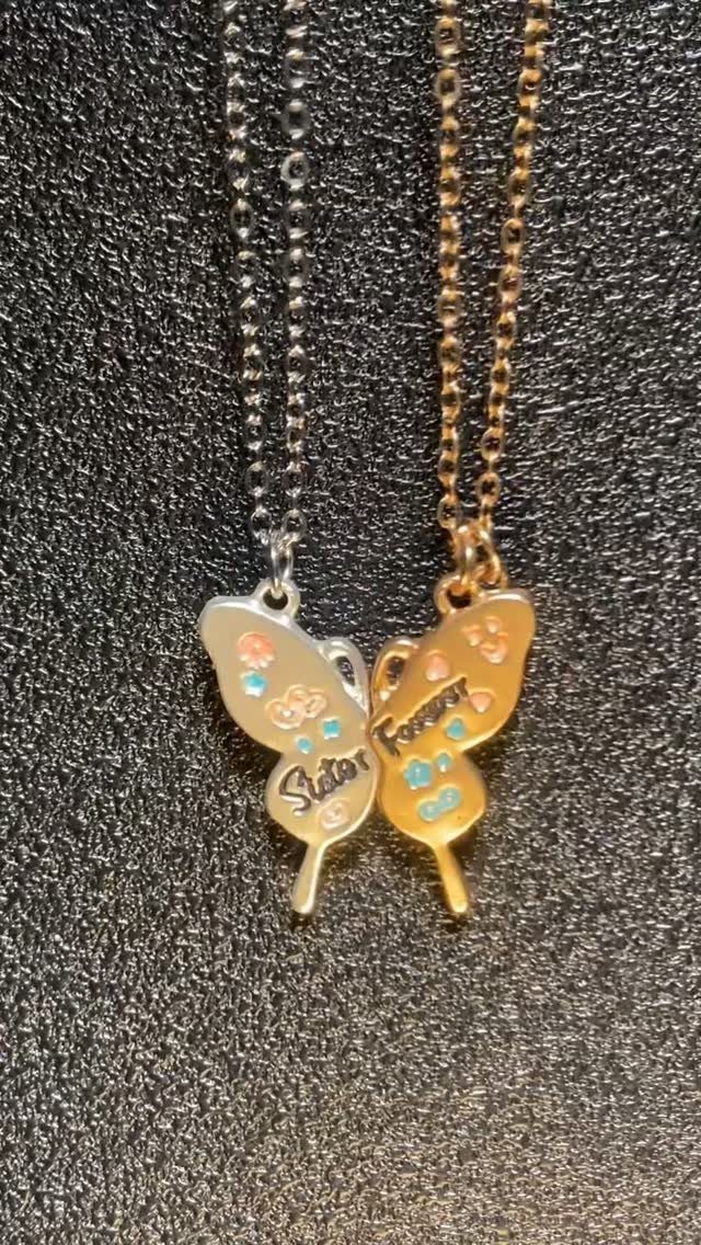Two matching butterfly necklaces, one silver and one gold, forming a complete butterfly.