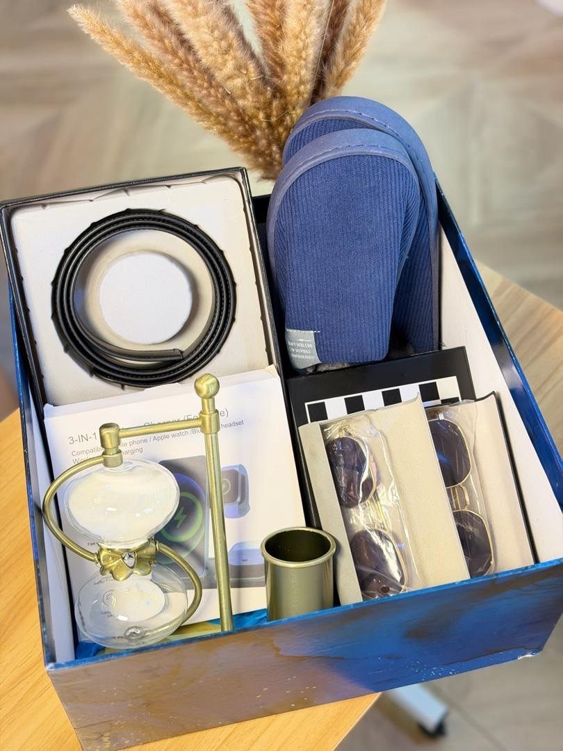 13 Ideas for a Birthday Gift for a Man Who Has Everything 12 Blue gift box filled with a belt, slippers, sunglasses, and a small hourglass.