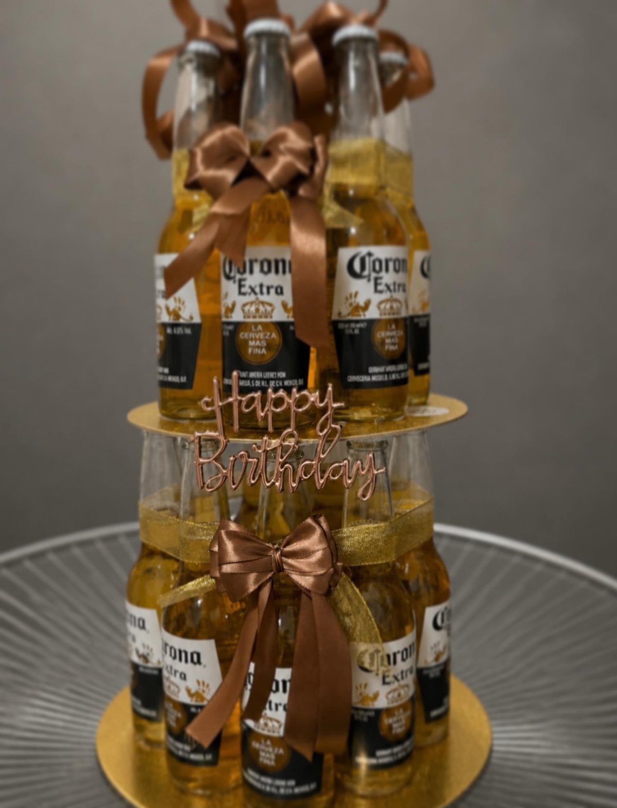13 Ideas for a Birthday Gift for a Man Who Has Everything 5 Beer bottle cake made of Corona Extra bottles with brown ribbons and birthday topper.