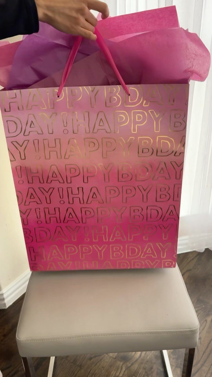 Birthday Gift Wrapping Ideas: 9 Ways to Wrap a Present 2 Pink and gold birthday gift bag filled with pink tissue paper on a chair