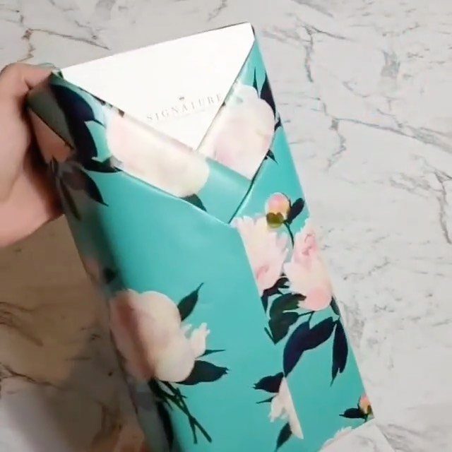 Birthday Gift Wrapping Ideas: 9 Ways to Wrap a Present 9 Gift wrapped in turquoise floral paper held against a white marble surface
