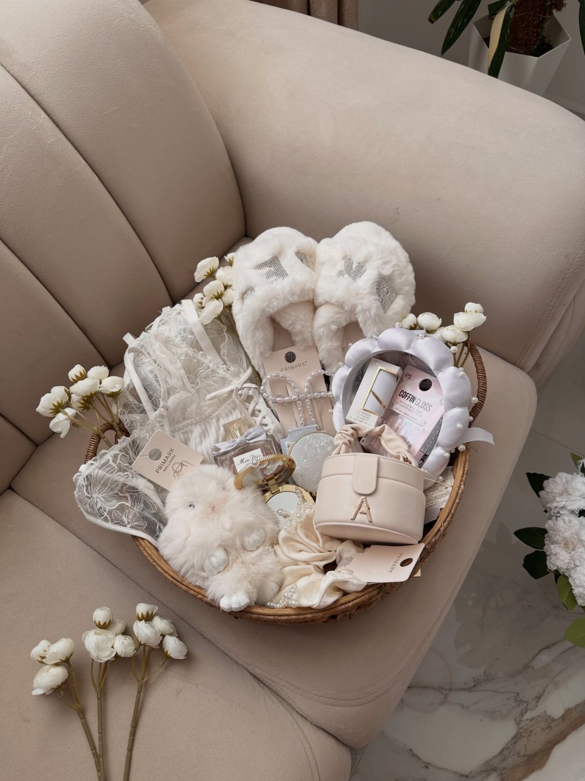 11 Bridal Shower Gift Basket Ideas for Every Bride-to-Be 4 Wicker gift basket with white fluffy slippers, lace, and beauty products on a sofa