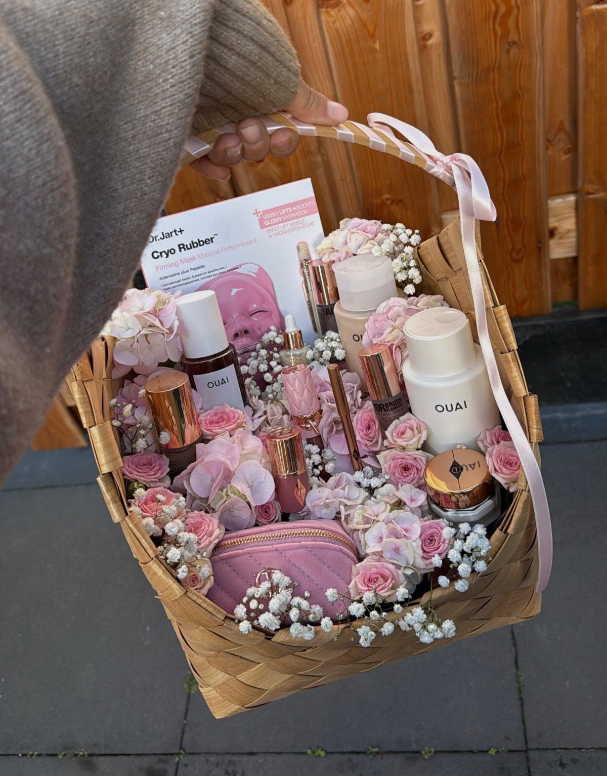 11 Bridal Shower Gift Basket Ideas for Every Bride-to-Be 8 Woven gift basket filled with pink beauty products and delicate pink and white flowers.