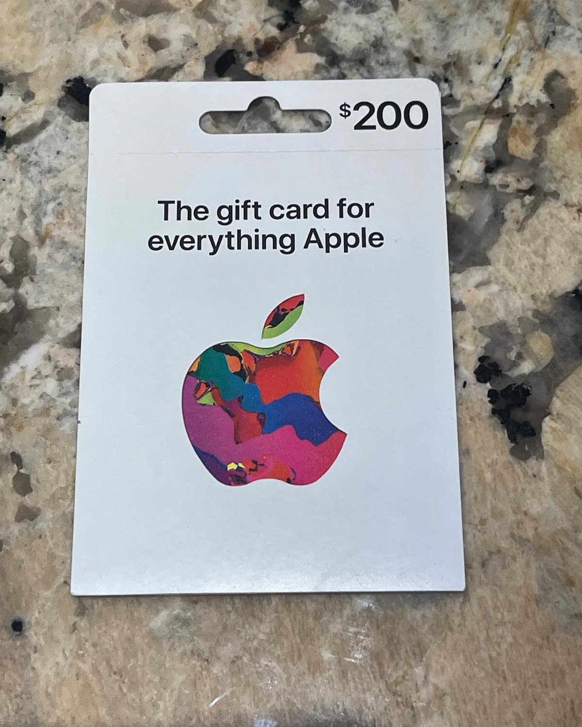 Apple gift card with colorful logo resting on a granite countertop