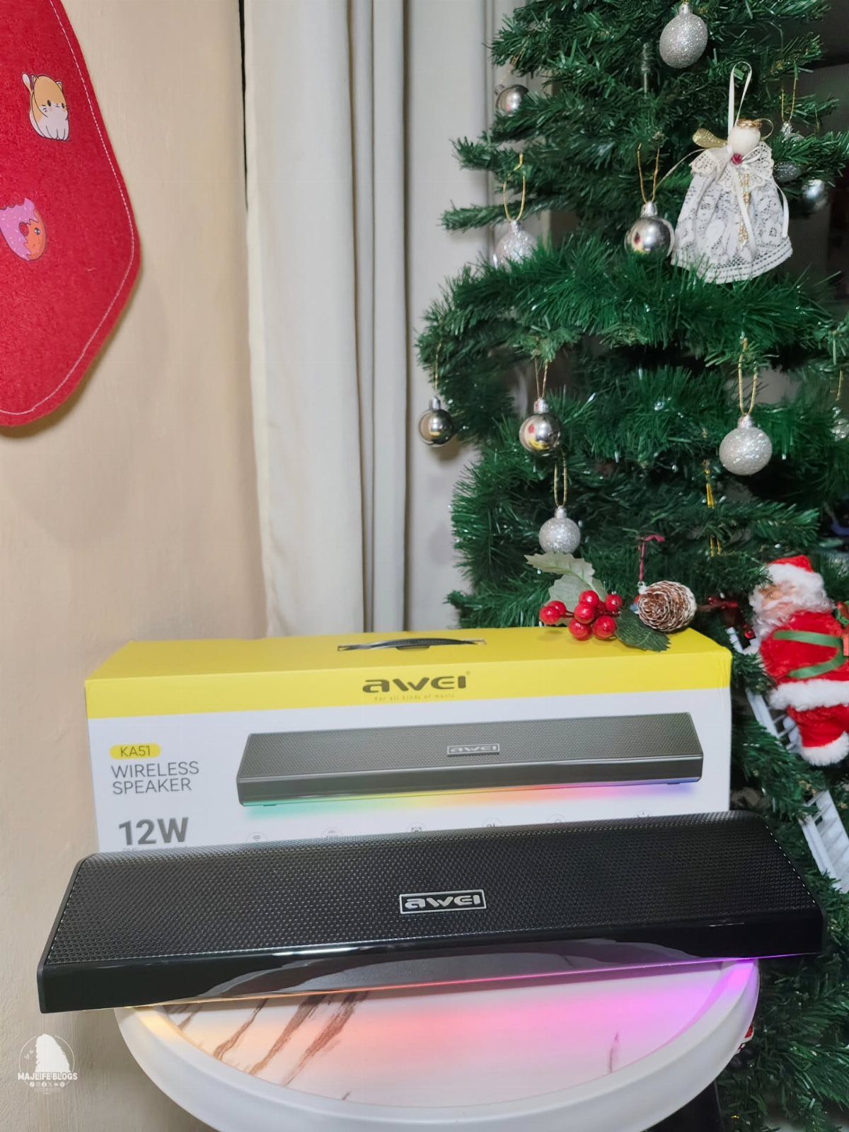 Wireless speaker and yellow box on a table next to a decorated Christmas tree