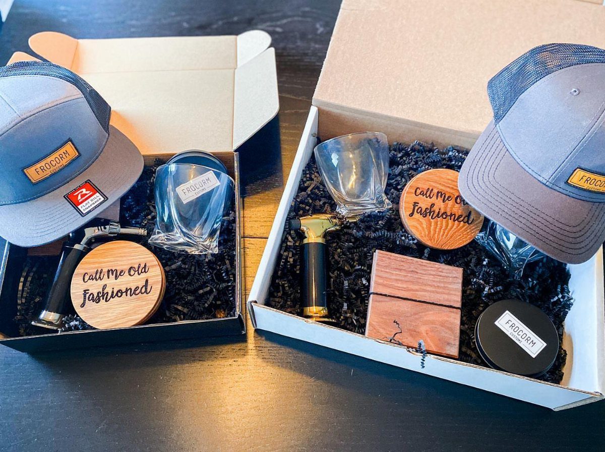 9 Cheap Fathers Day Gifts with Handmade and Easy Ideas 6 Two gift boxes containing grey caps, glassware, and wooden coasters on a dark table.