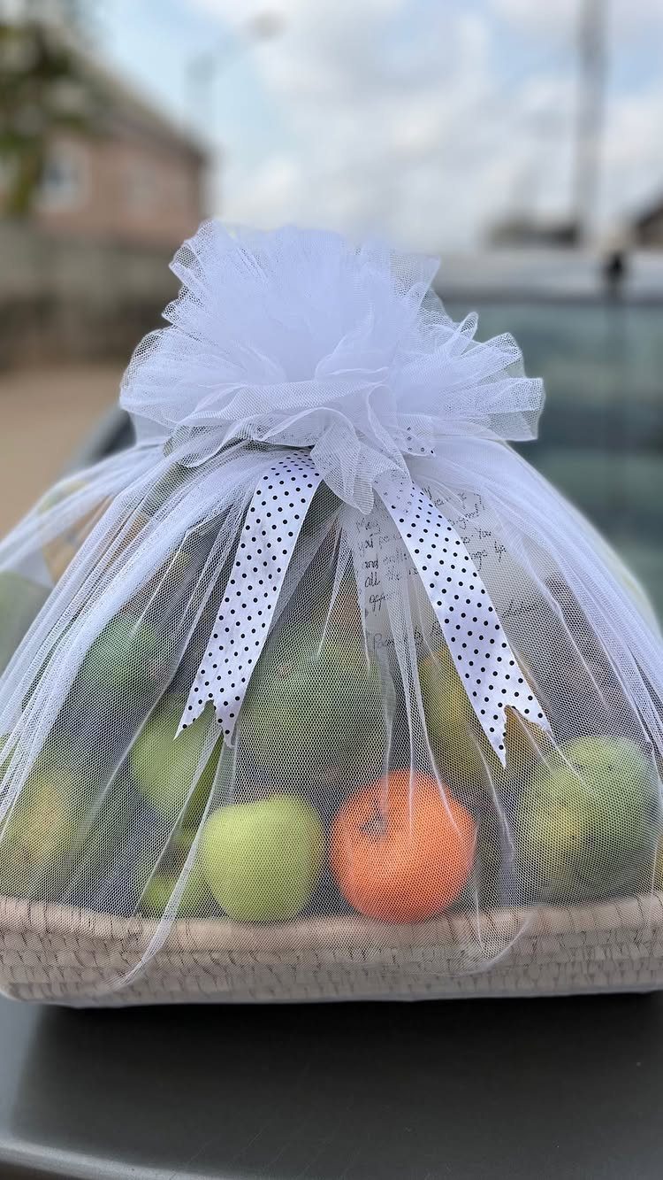 Christmas Food Basket Gift Ideas: 10 Options to Give 4 Woven basket of red and green apples wrapped in white tulle and ribbon.