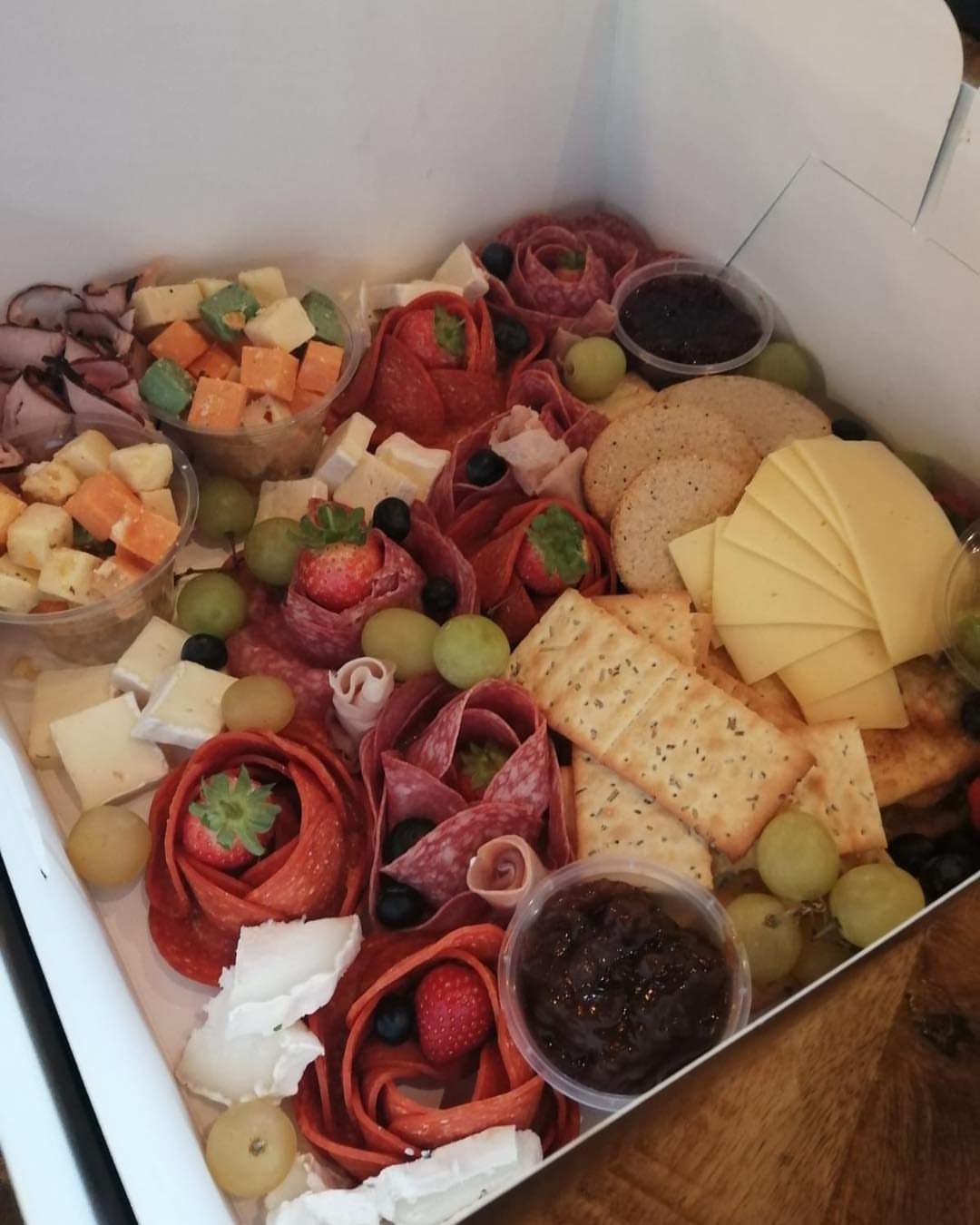 Christmas Food Basket Gift Ideas: 10 Options to Give 3 Meat and cheese gift box with salami roses, crackers, grapes, and strawberries.