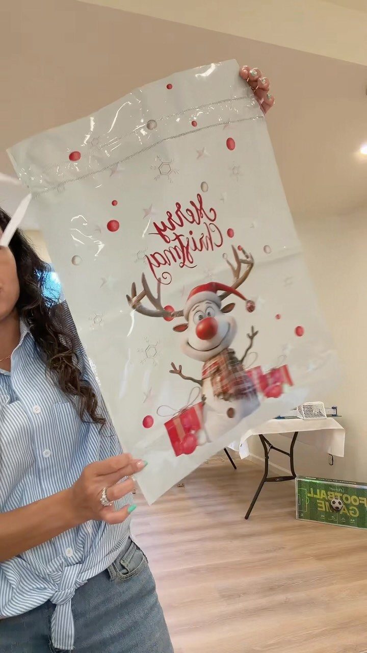 Christmas Gift Wrapping: 5 Ideas for Paper, Bows and Bags 3 White glossy Christmas gift bag with a cartoon reindeer held by a person.