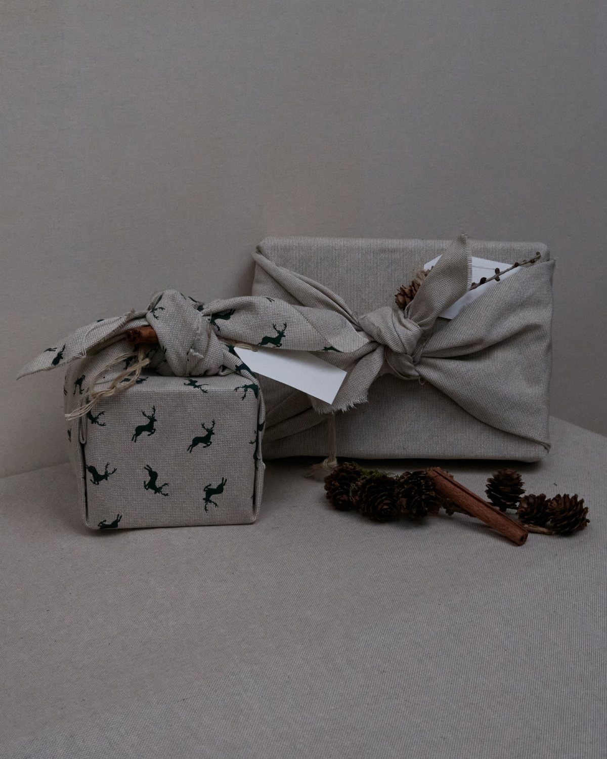 Christmas Gift Wrapping: 5 Ideas for Paper, Bows and Bags 5 Fabric wrapped gifts with deer patterns, tied with bows and decorated with pinecones.