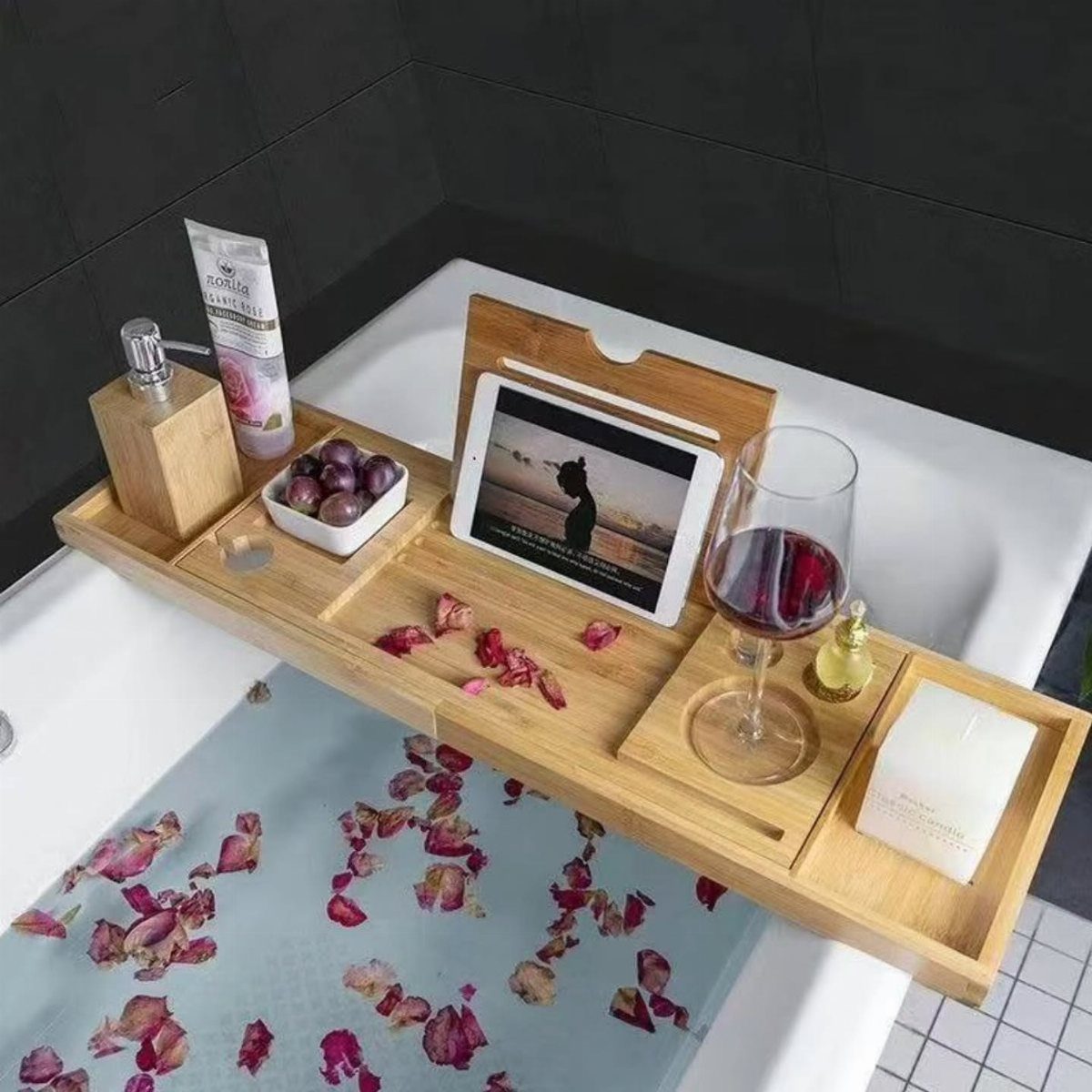 11 Christmas Gifts for Adults, From Waffle Makers to Desks 1 Bamboo bathtub caddy holding a tablet, wine, and grapes over a petal-filled bath