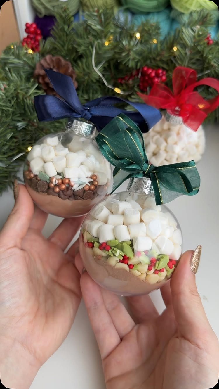25 Christmas Gifts to Make at Home: Candles to Cookies 4 Hot cocoa mix in clear ornament jars with ribbons held by two hands.