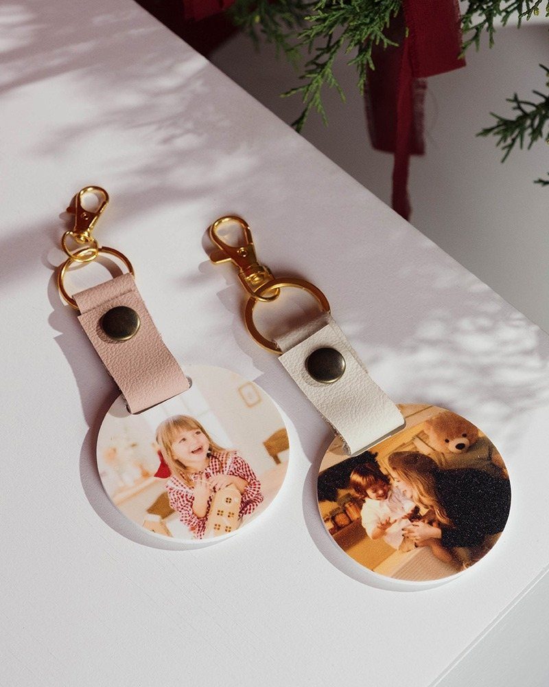 25 Christmas Gifts to Make at Home: Candles to Cookies 13 Two personalized photo keychains with leather straps and gold metal clasps on white.