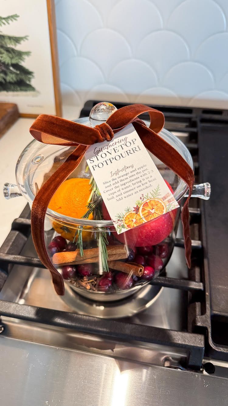 25 Christmas Gifts to Make at Home: Candles to Cookies 3 Glass pot of stovetop potpourri with citrus, cinnamon, and cranberries on a stove.