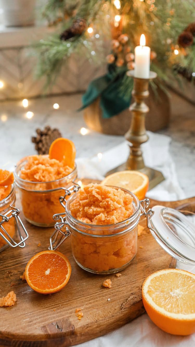 25 Christmas Gifts to Make at Home: Candles to Cookies 2 Orange sugar scrubs in small glass jars on a wooden board with citrus slices