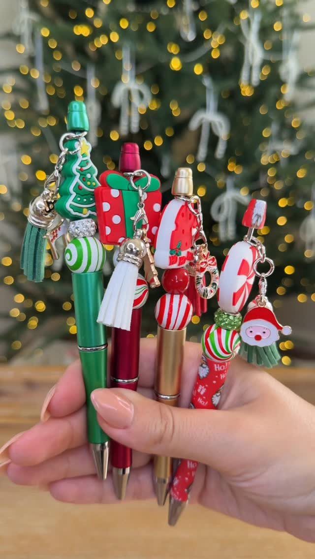Christmas Stocking Gifts: 8 Small Ideas, Socks to Puzzles 6 Four decorative Christmas pens with festive charms held in a person's hand.