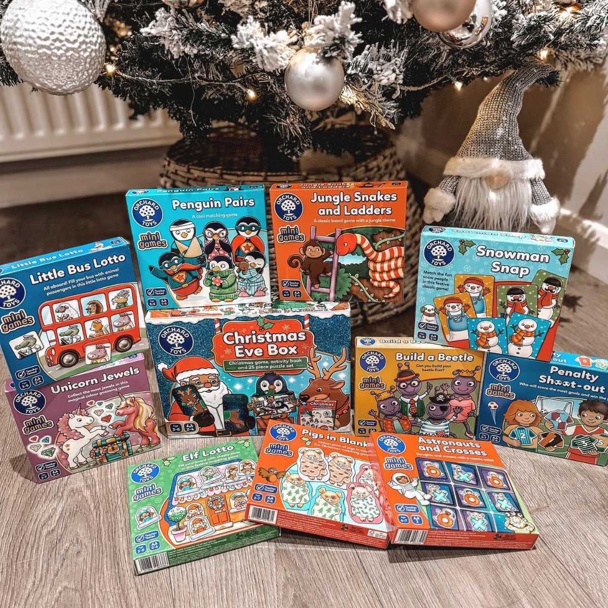 Christmas Stocking Gifts: 8 Small Ideas, Socks to Puzzles 4 Small colorful board game boxes arranged on a floor under a Christmas tree.