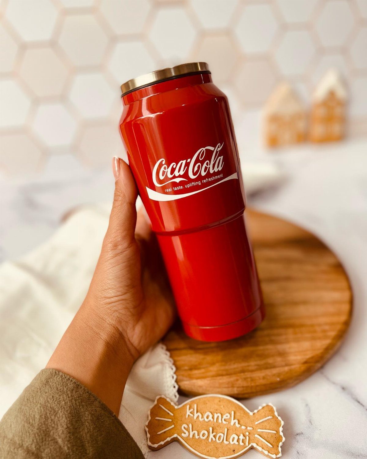Coca-Cola Christmas Gift Ideas: 7 Picks for Fans 3 Red Coca-Cola branded insulated tumbler held by a hand over a wooden board.