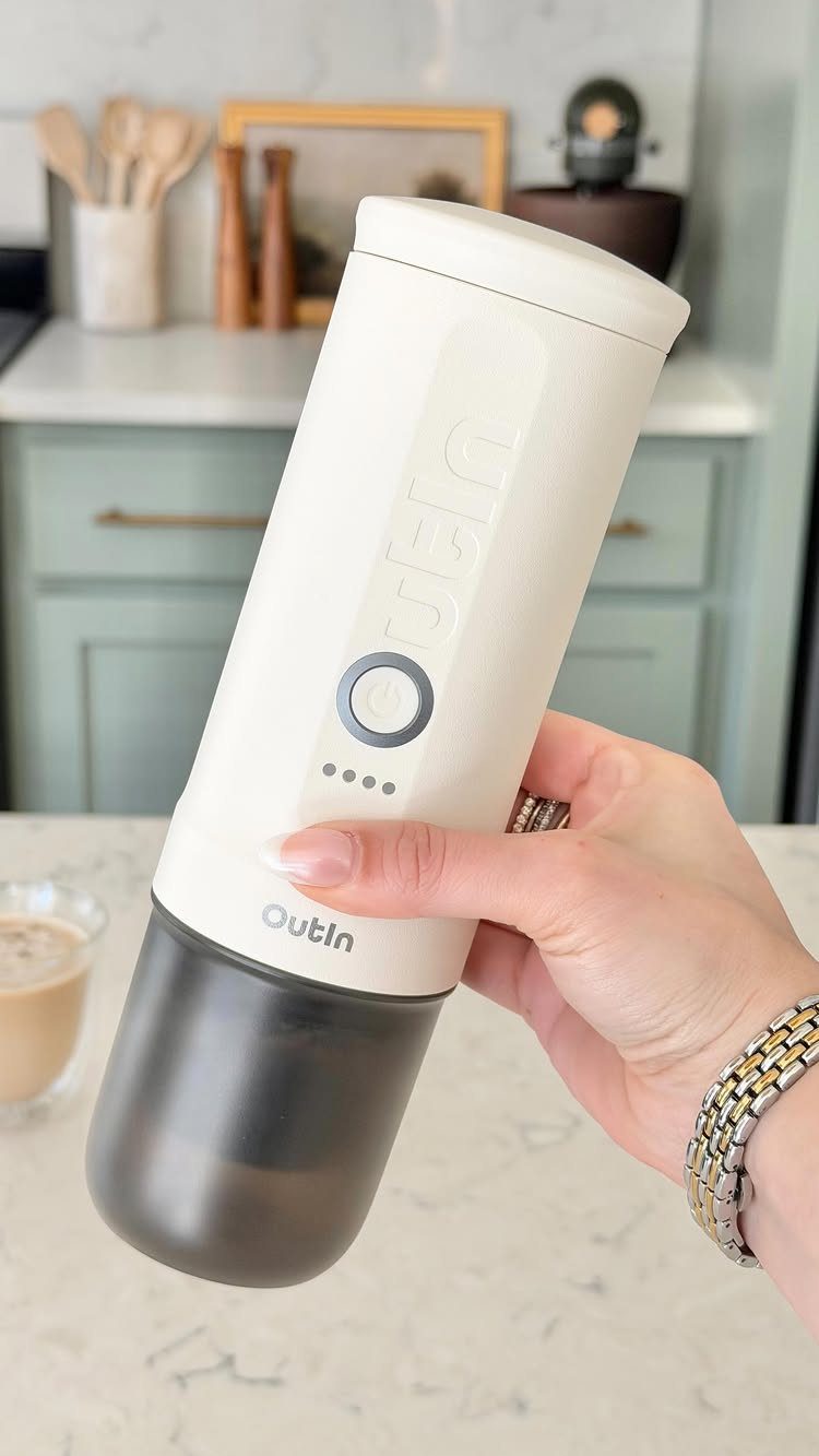 7 Coffee Gift Ideas for the Caffeine Fan on Your List 4 Portable espresso maker held in a hand against a blurred kitchen background.