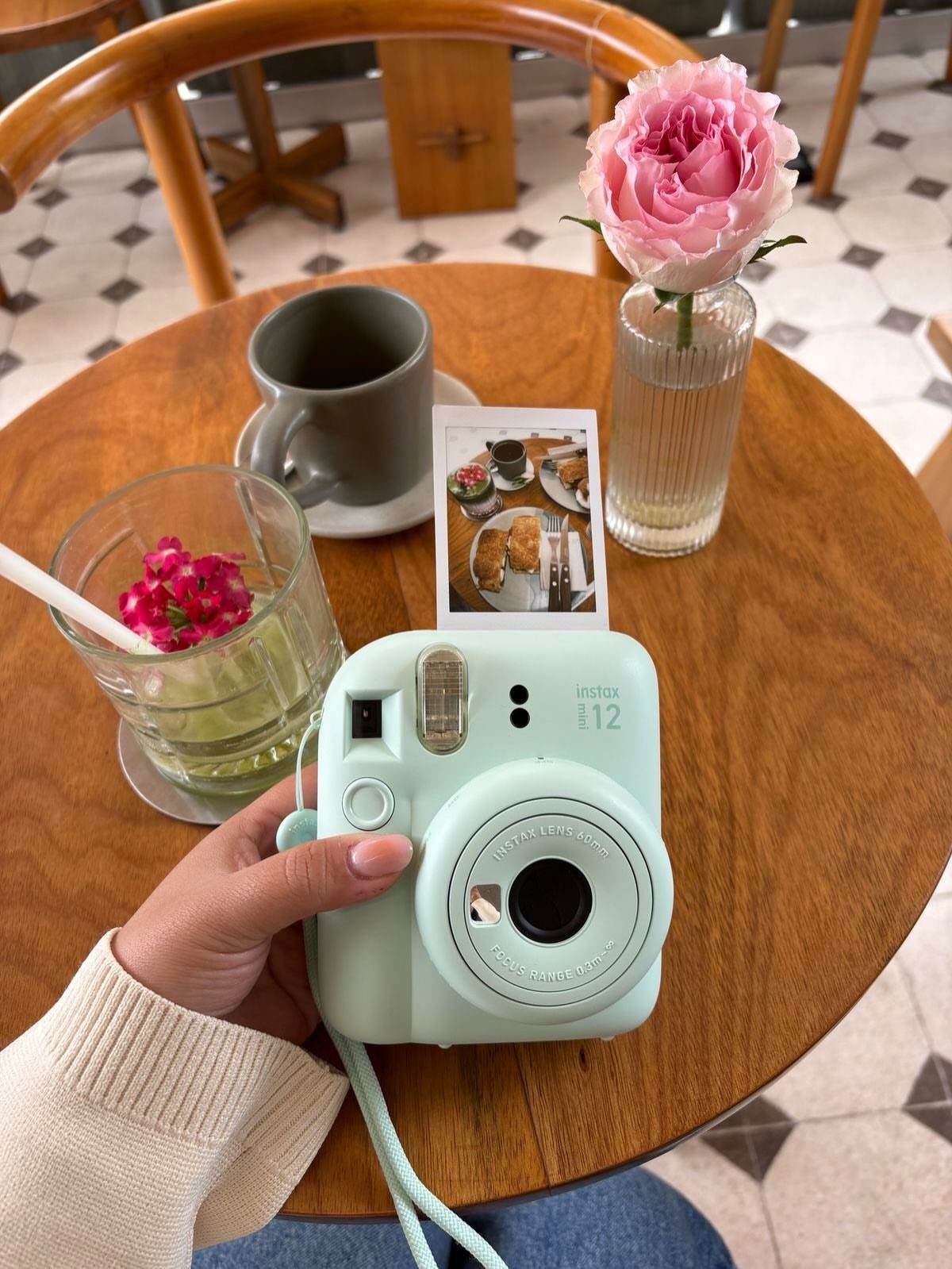 17 Creative Birthday Gifts for Friends and Family 3 Mint green Instax mini camera held over a cafe table with a rose.