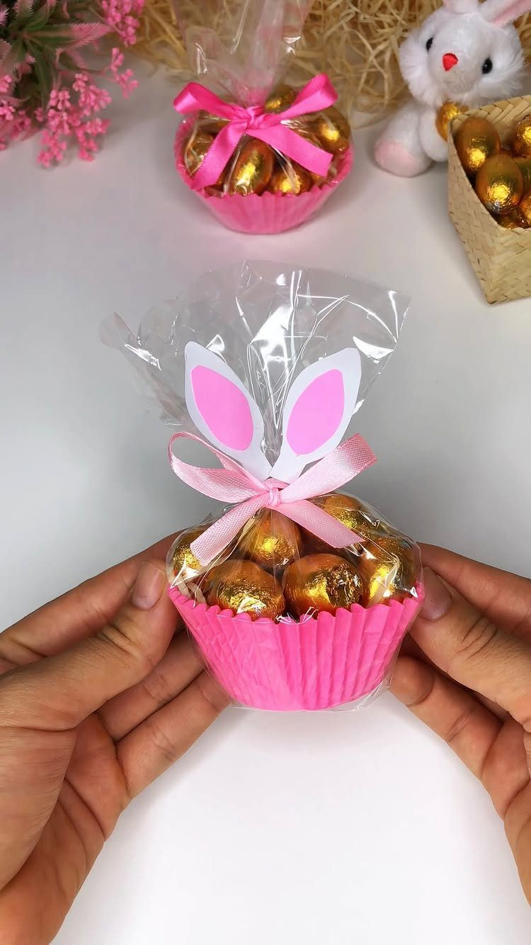 Gold-foil chocolates in a pink liner with bunny ear decorations and pink ribbon.