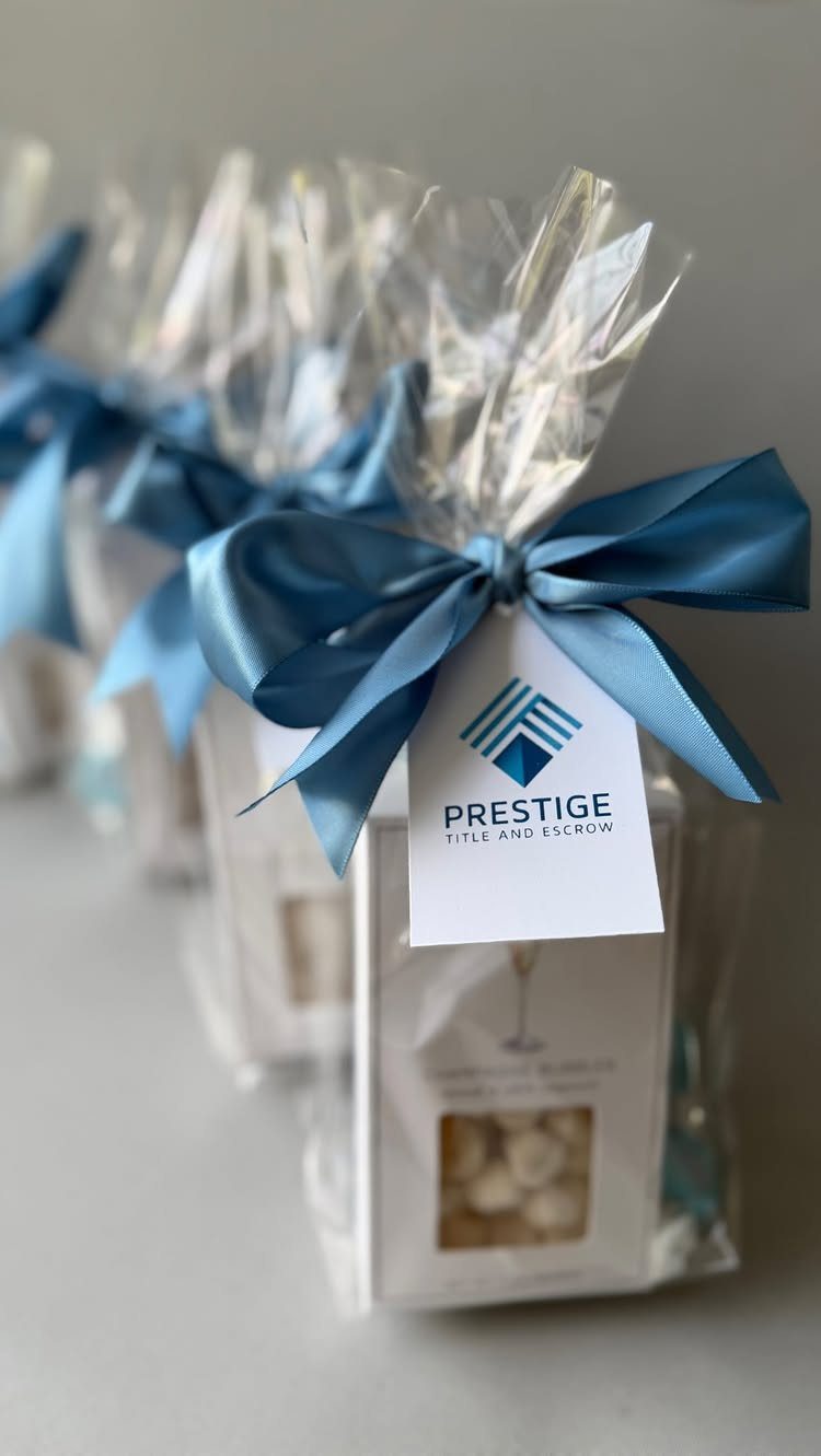 Clear cellophane gift bags with blue satin bows and corporate branded tags.