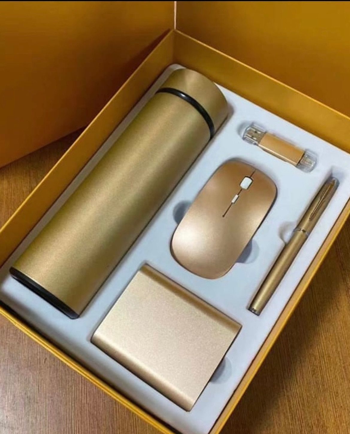 Gold metallic gift set with thermos, mouse, pen, and power bank in yellow box