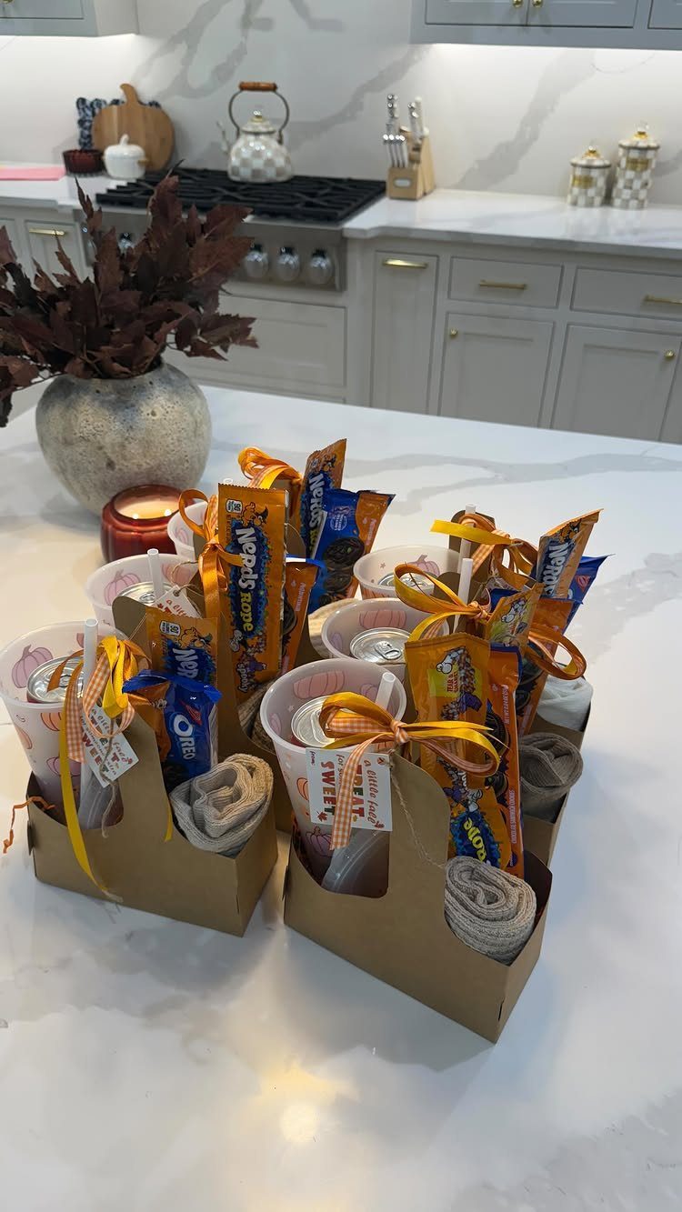 Small brown gift carriers with snacks and ribbons on a white marble counter.