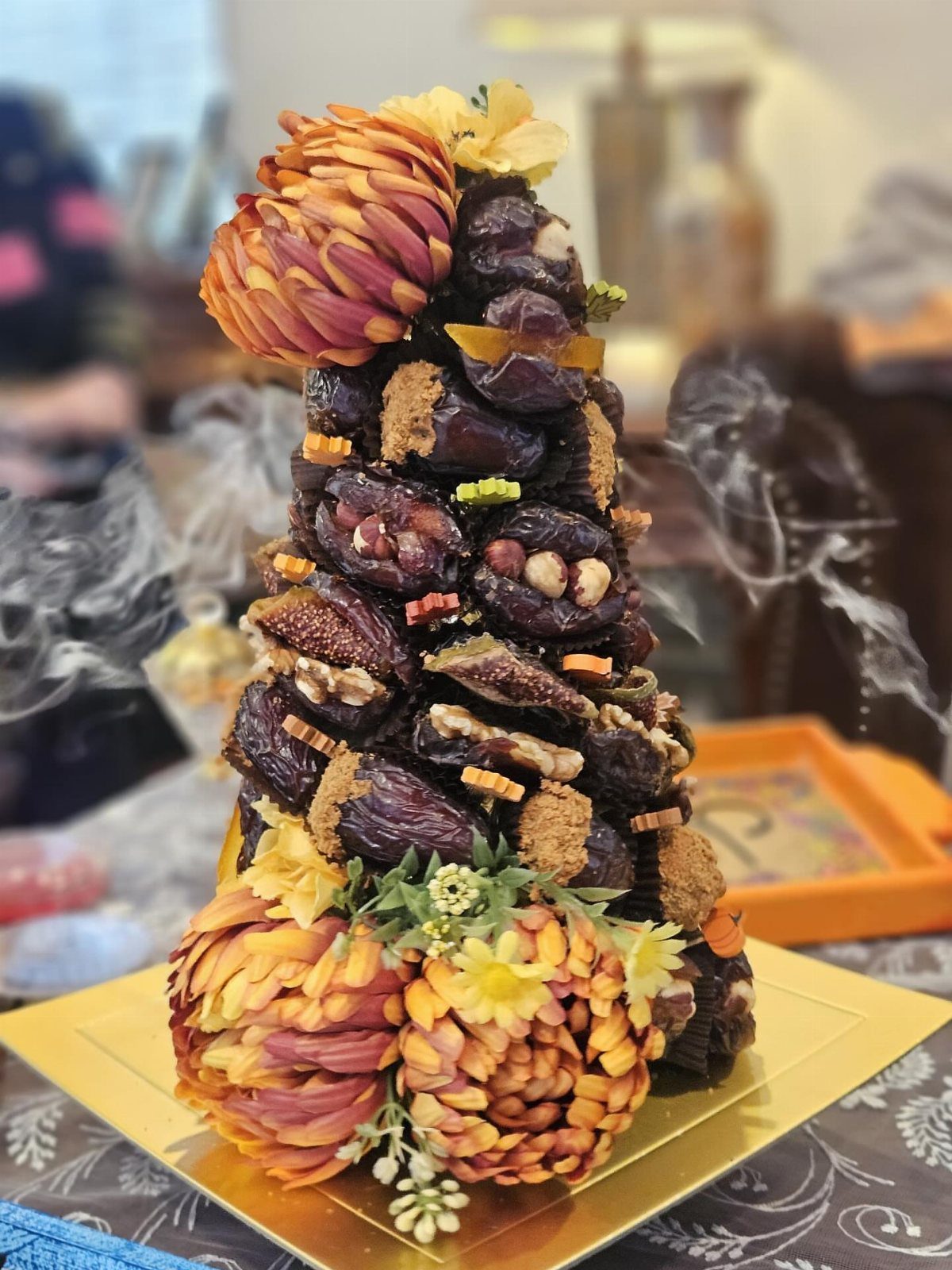 Tower of stuffed dates and nuts decorated with orange edible flower garnishes.