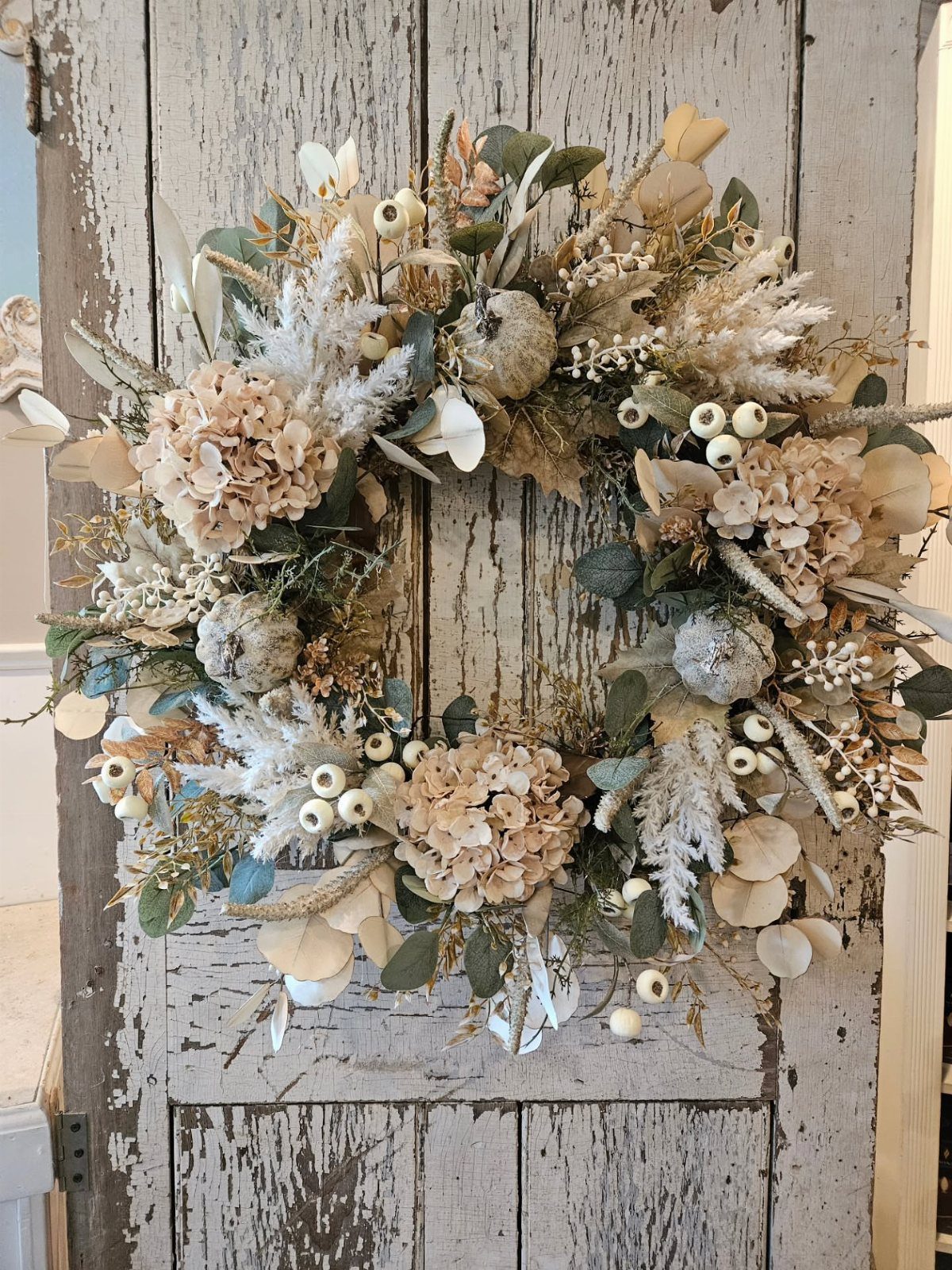 13 Fall Gifts for Women, From Cozy Socks to Cookbooks 10 Autumn wreath with dried flowers and pampas grass on a rustic white door