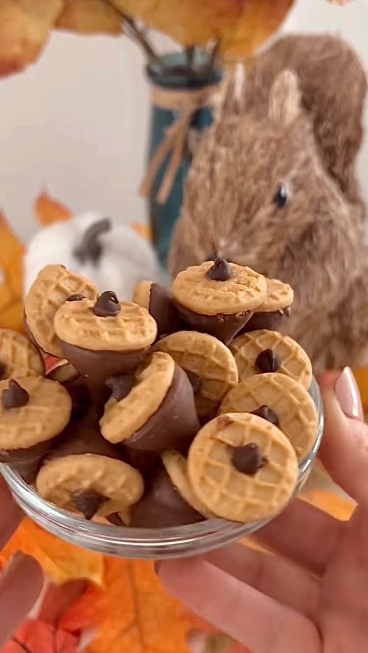 13 Fall Gifts for Women, From Cozy Socks to Cookbooks 9 Acorn-shaped chocolate and cookie treats in a glass bowl with autumn decorations.