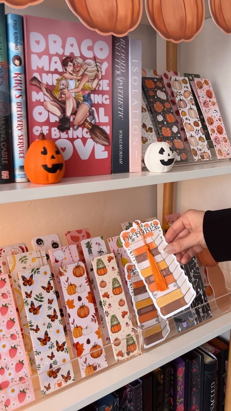 Fall-themed bookmarks in an acrylic organizer on a shelf with autumn decorations.
