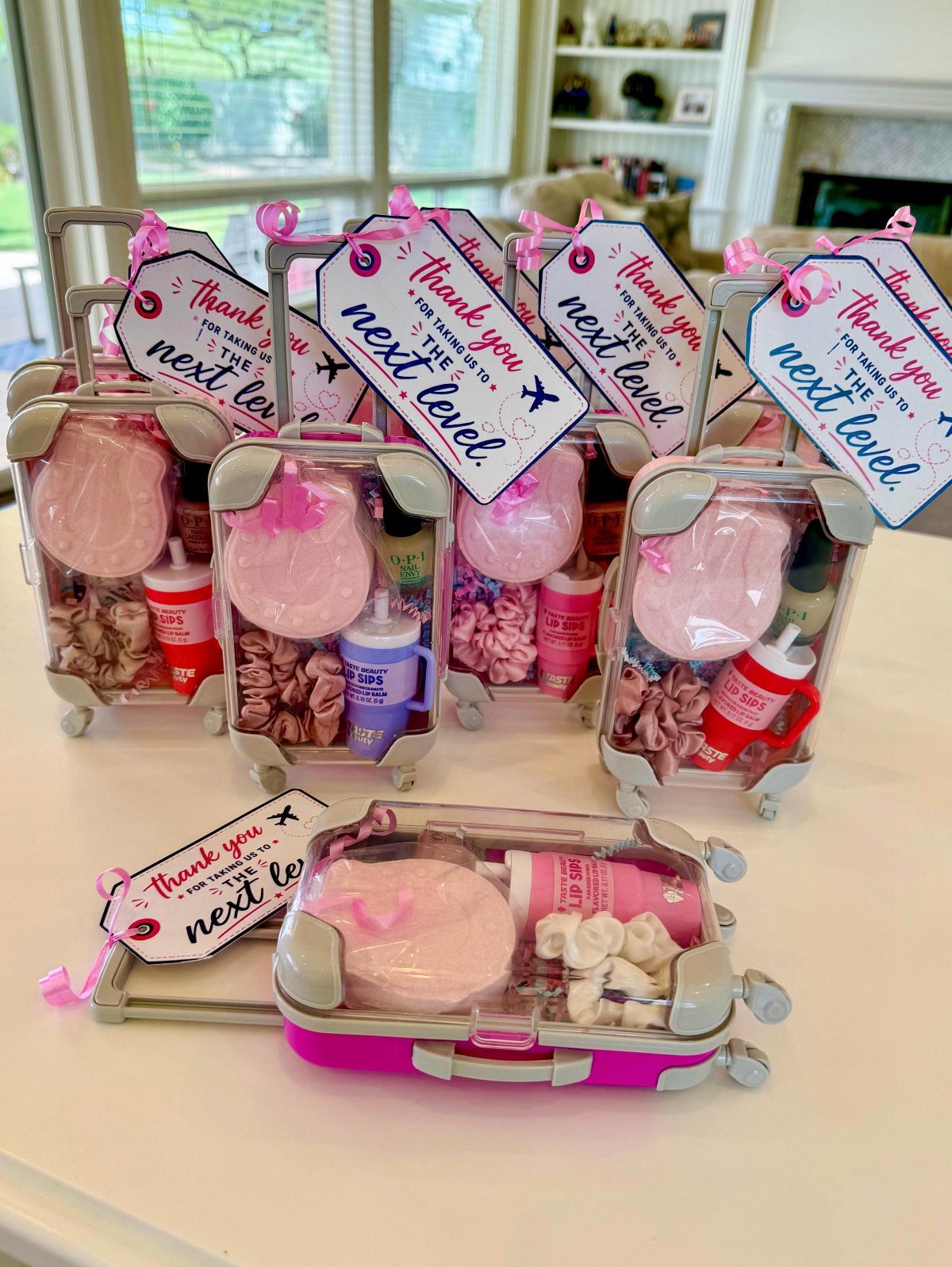 Small suitcase gift boxes filled with pink treats and thank you tags.