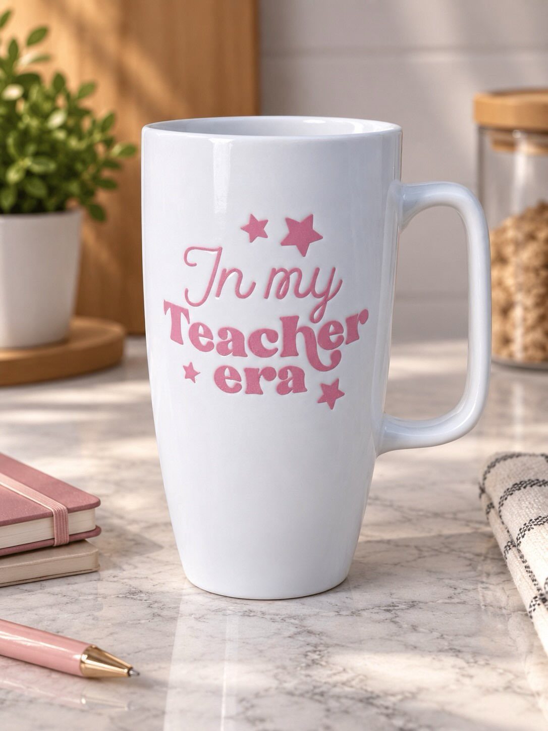 White ceramic travel mug with pink In my Teacher era text on marble surface