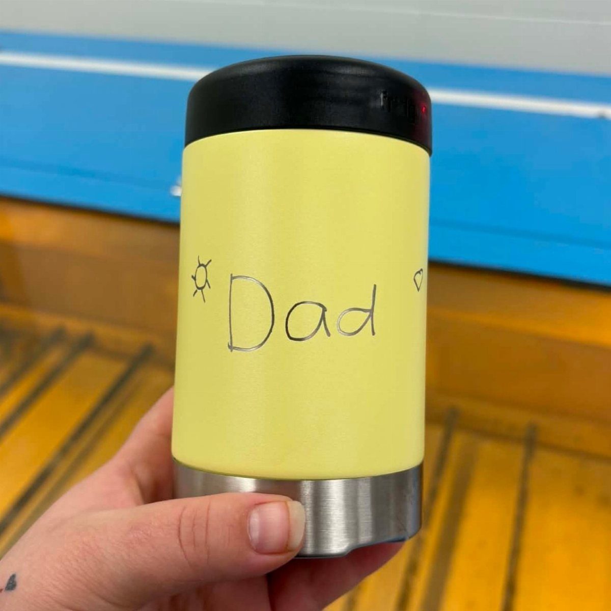 8 Father's Day Gift for Employees Ideas Dads Will Use 1 Yellow insulated travel mug with Dad handwritten on it held by a hand