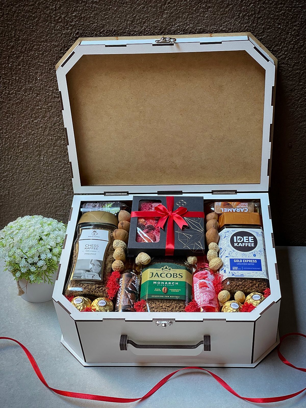 Gourmet gift box in a white suitcase containing coffee jars and assorted sweets.
