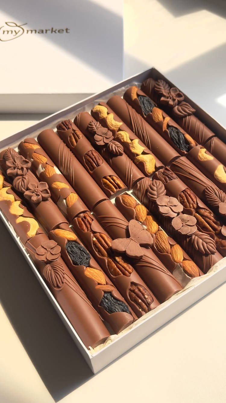 Assorted gourmet chocolate cylinders with nuts and dried fruits in a white gift box