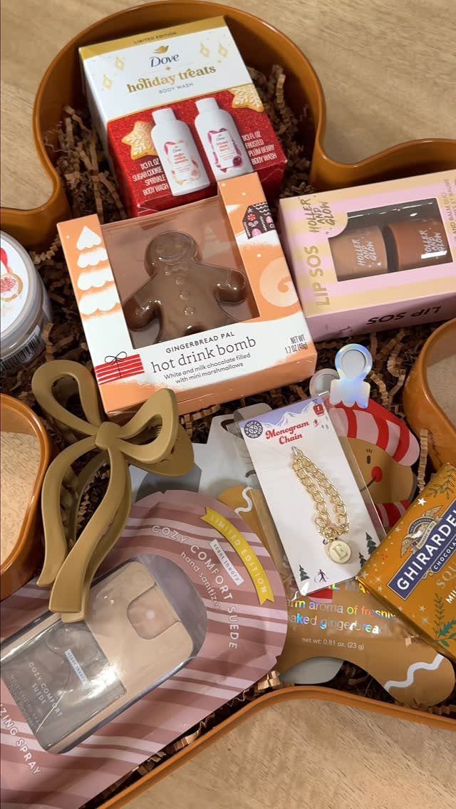 Gift basket filled with holiday treats, skincare, and jewelry on brown shredded paper.