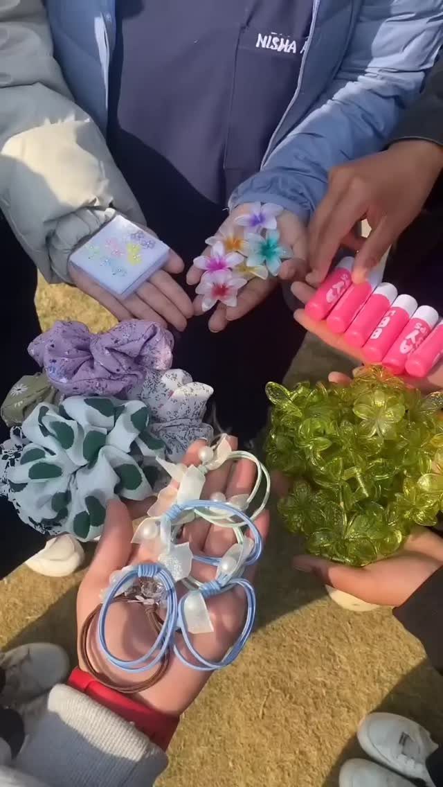 Hands holding handmade gifts including beaded bracelets, scrunchies, and colorful flower accessories.
