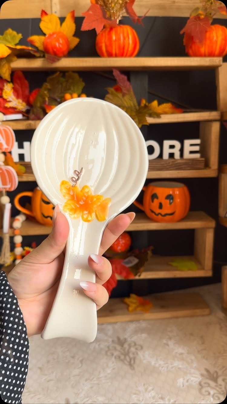 15 Friendsgiving Gift Ideas for Hosts and Guests 11 White ceramic leaf-shaped dish held in hand against a fall-themed background.