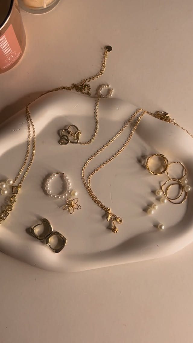 15 Friendsgiving Gift Ideas for Hosts and Guests 2 White ceramic jewelry dish holding gold necklaces, rings, and pearl accessories.